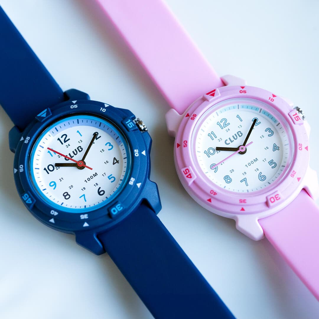 To armbåndsur med gummireimer, ett marineblått og et rosa. Hvert ur har en hvit urskive med arabiske tall og svarte visere.