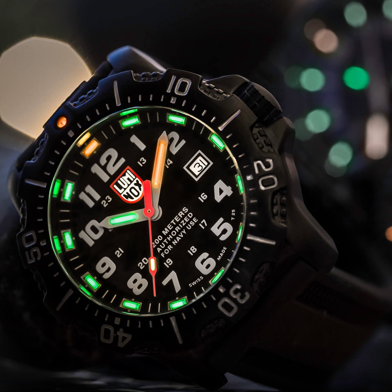 Nærbilde av et robust svart armbåndsur med lysende grønne og oransje visere, glødende tall og datovisning, mot en uskarp bakgrunn.