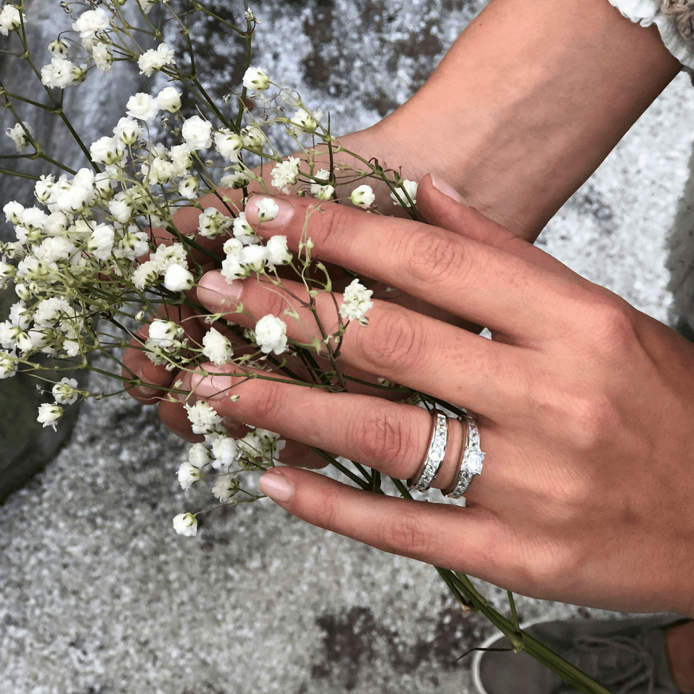 To sølvringer med rektangulære zirkonia-steiner, den ene med forhøyet midtstein i firkantet slip.