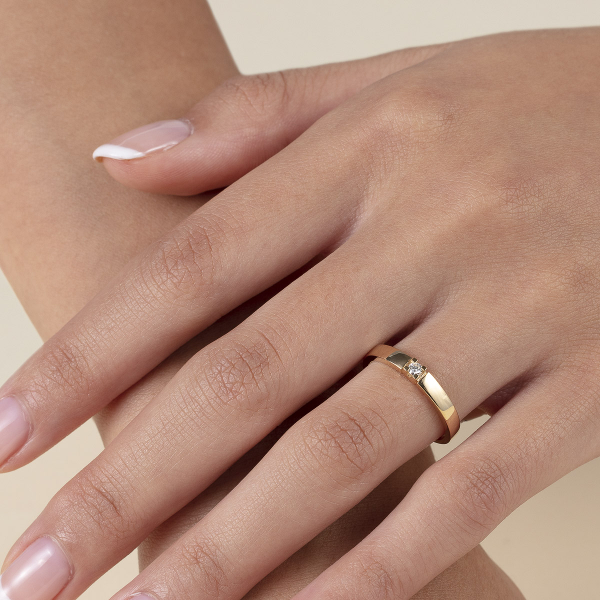 Gullring med en enkel rund diamant festet i midten, vist mot hvit bakgrunn.