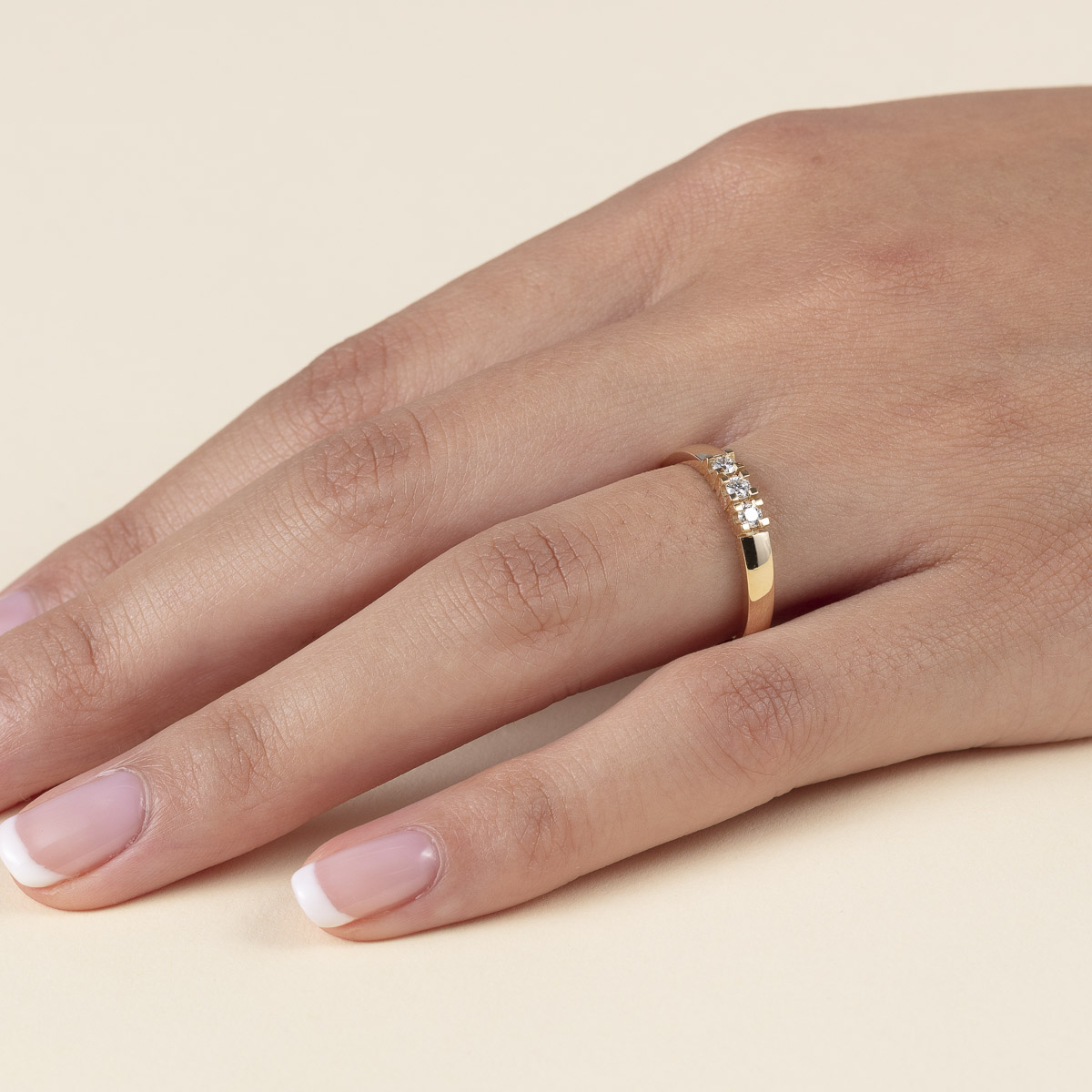 Gullring med tre diamanter i klørfesting, fotografert mot hvit bakgrunn med skygge under ringen.