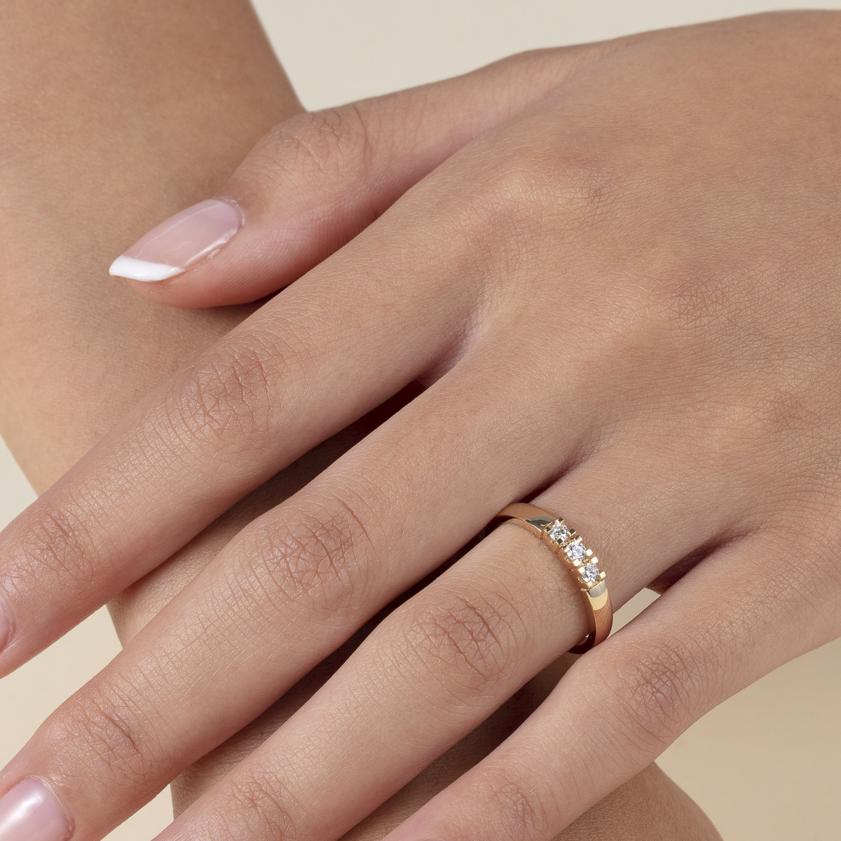 Gullring med tre diamanter i klørfesting, fotografert mot hvit bakgrunn med skygge under ringen.