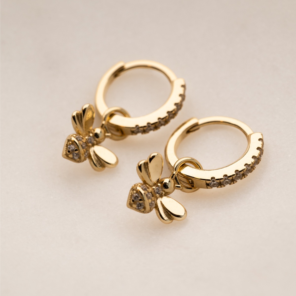 Gylne øreringer med små bianheng dekorert med klare stener på både ringer og anheng