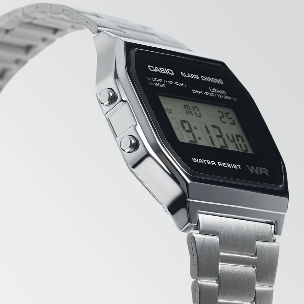 Sølvfarget digital armbåndsur med rektangulær skjerm som viser klokkeslettet 10:58:50 og tekst om alarm og vannmotstand.