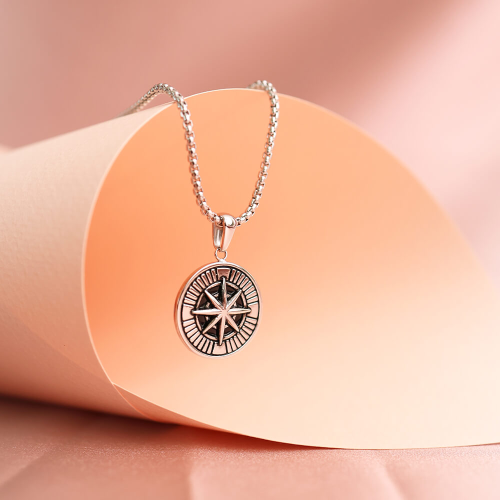 Tøft halssmykke i grått metall med sirkelanheng, motiv av kompass og nautisk stjerne.