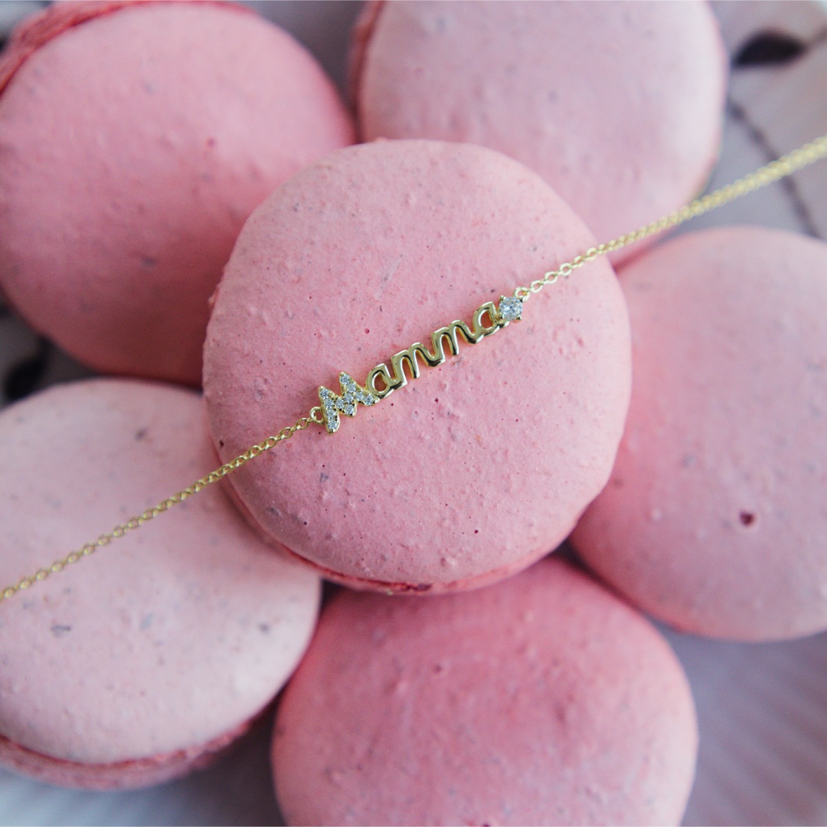 Gullfarget armbånd med teksten “Mamma” i midten, pyntet med små klare stener på bokstavene