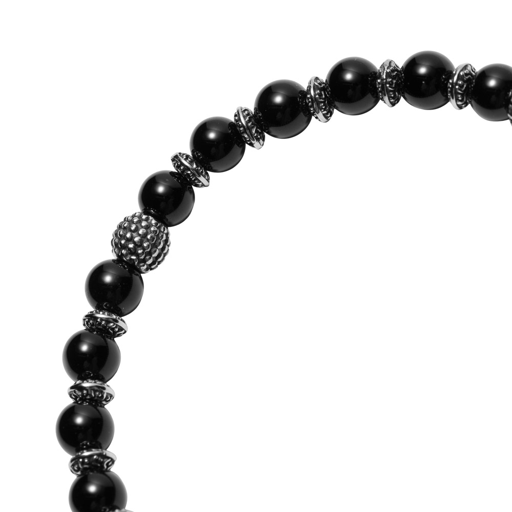 Elastisk armbånd med svarte kuler og detaljerte sølvfargede perler i metall, vist mot hvit bakgrunn.