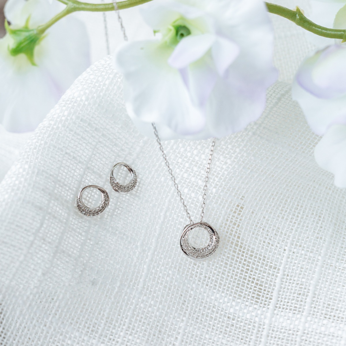 Diamantsmykke i hvitt gull med rund sirkelanheng og pavéfattet design, vist mot hvit bakgrunn.