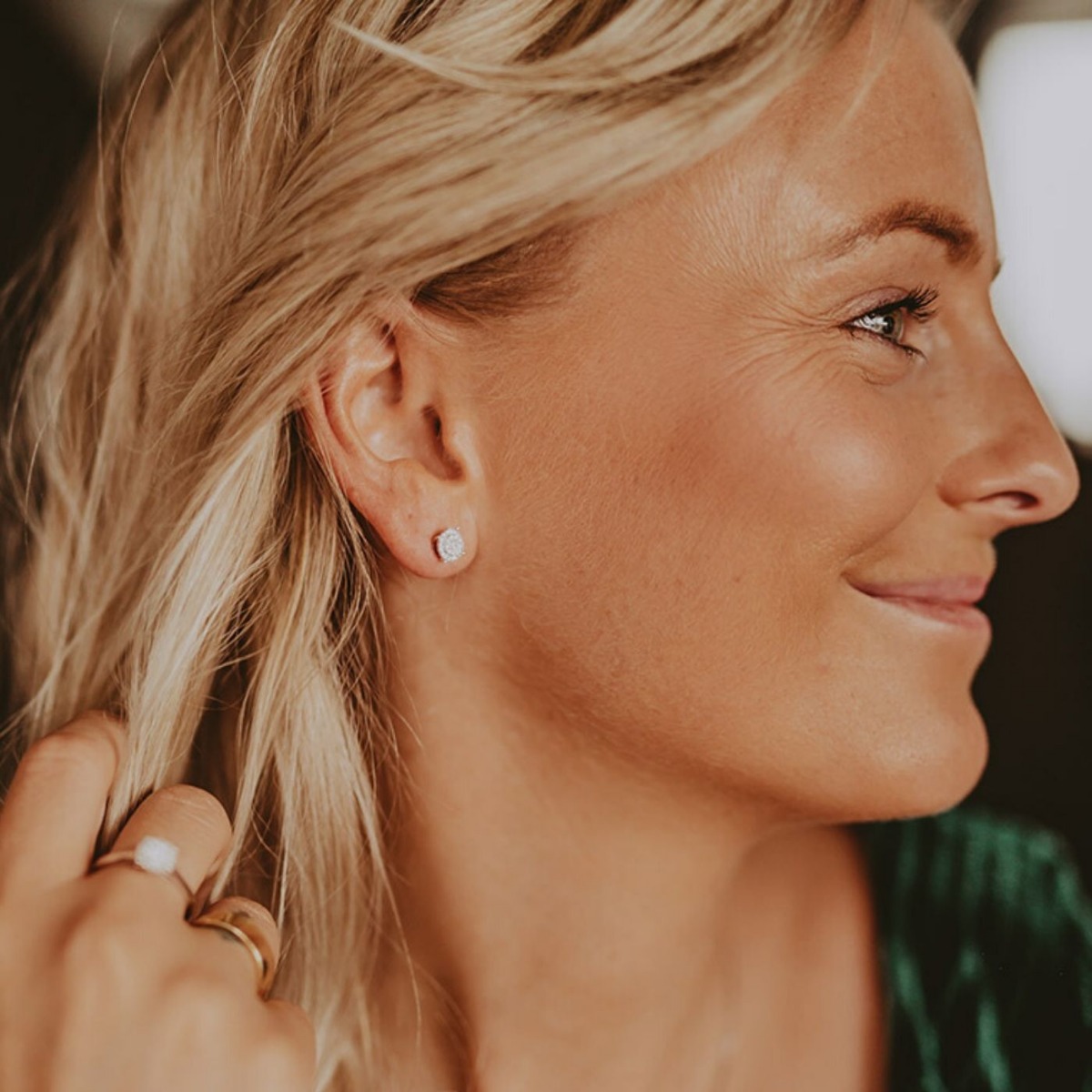 Øredobber i hvitt metall med runde klynger av små klare steiner, stift for øret med fjærlås, vist fra front og bakside