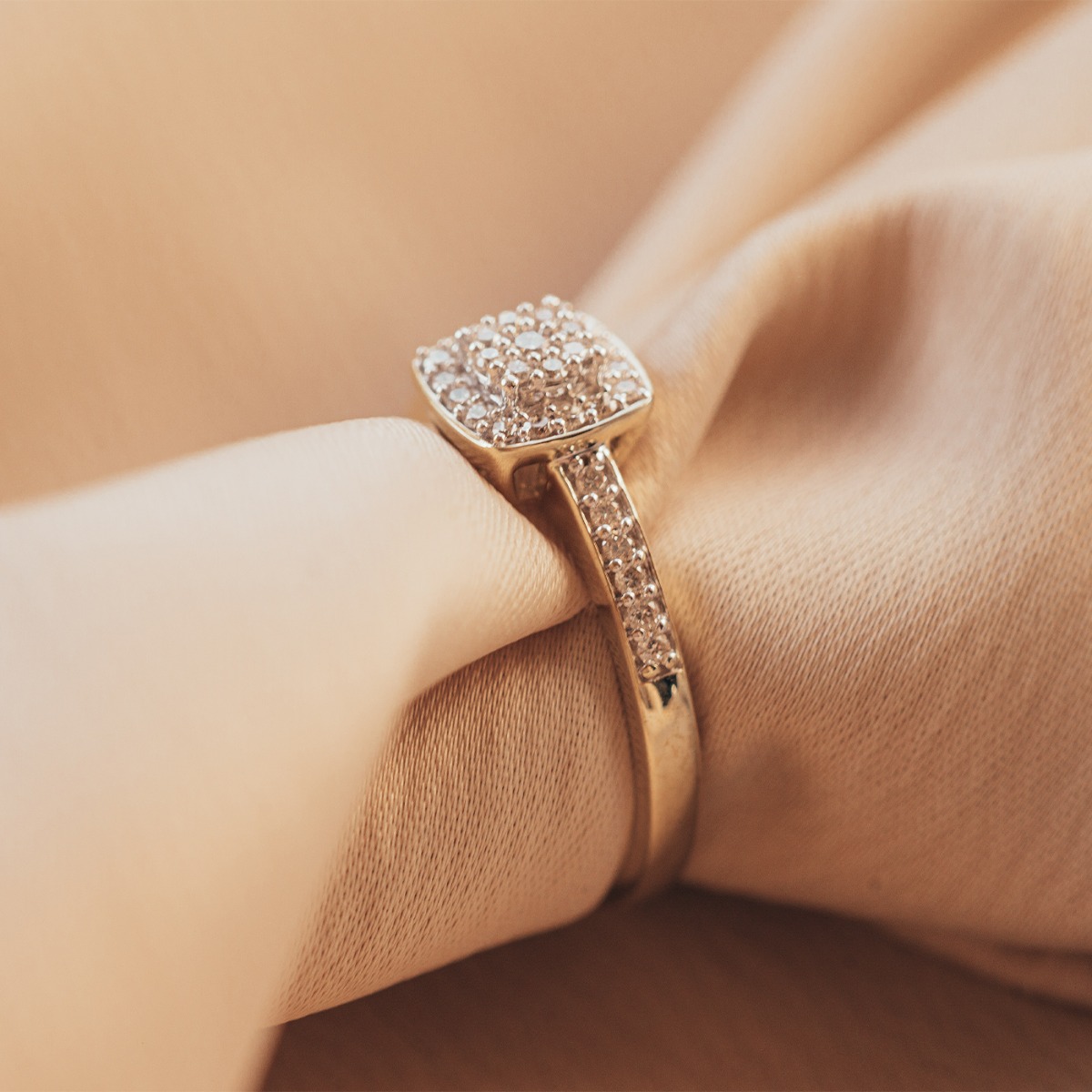 Sølvring med firkantet fatning dekorert med små diamanter og diamantbesatte skuldre, avbildet mot hvit bakgrunn.