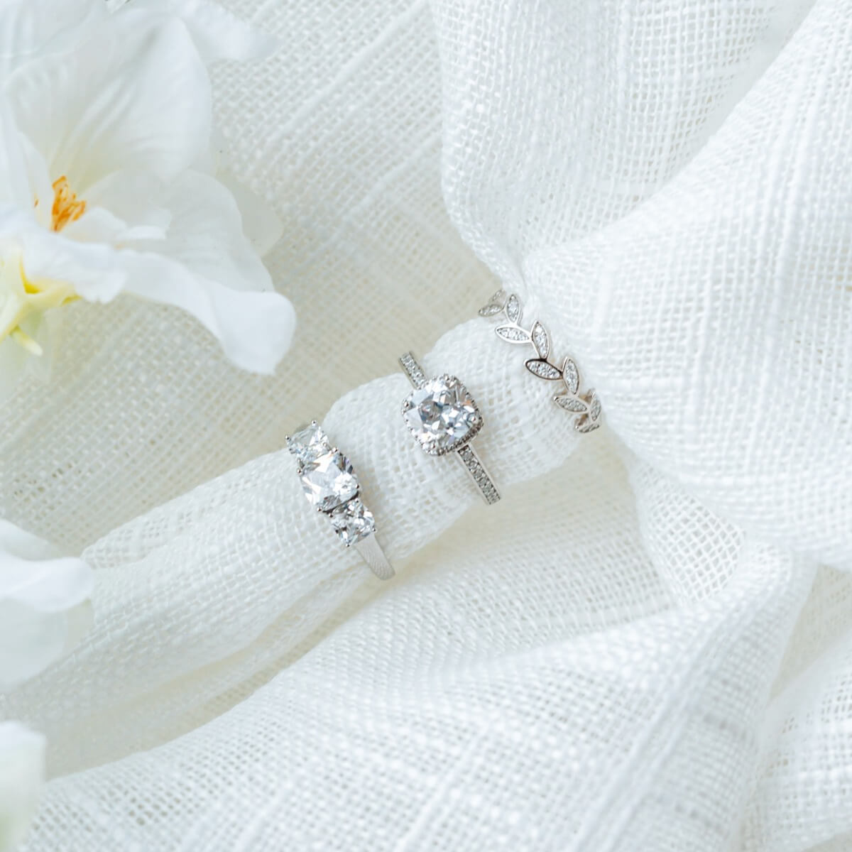 En sølvring med stor puteslipet diamant i kløfatning omgitt av krans av små diamanter og små diamanter i skinnen på hvit bakgrunn