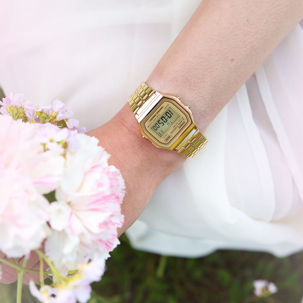 Gullfarget Casio digitalt armbåndsur med rektangulær urskive og lenke i metall på hvit bakgrunn.