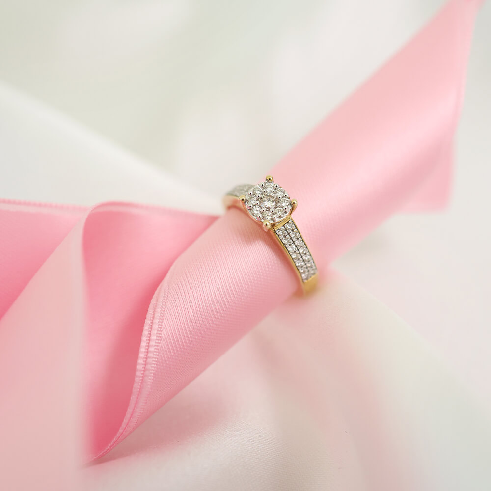 Gullring med rund midtsten omgitt av små klare stener, og flere små stener satt tett i rekker langs ringskinnen.