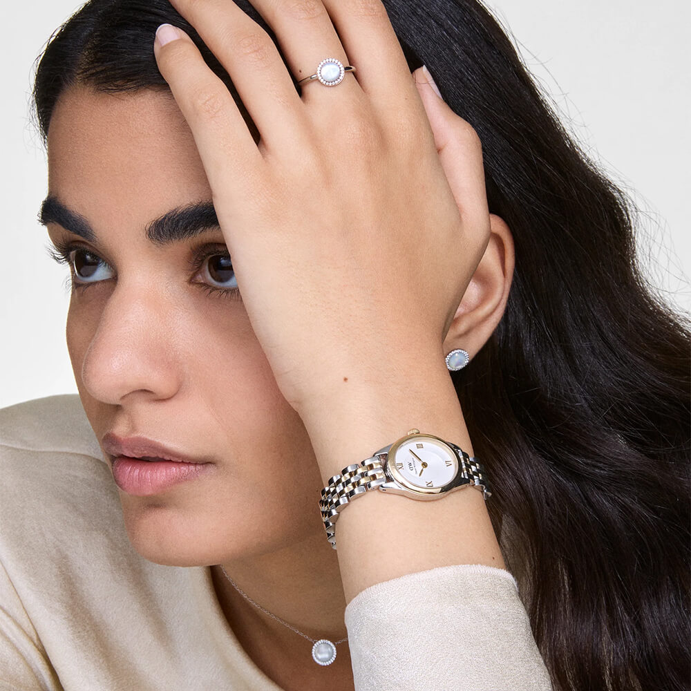 Tofarget armbåndsur i gull og sølv med hvit urskive og romertall, vist forfra mot hvit bakgrunn.