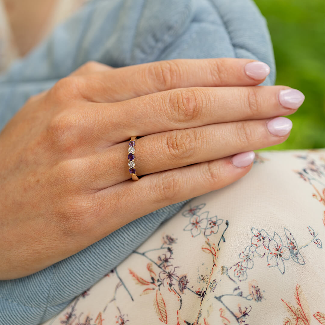 Vakker ring med lilla og hvite stener på gullfarget ringskinn.