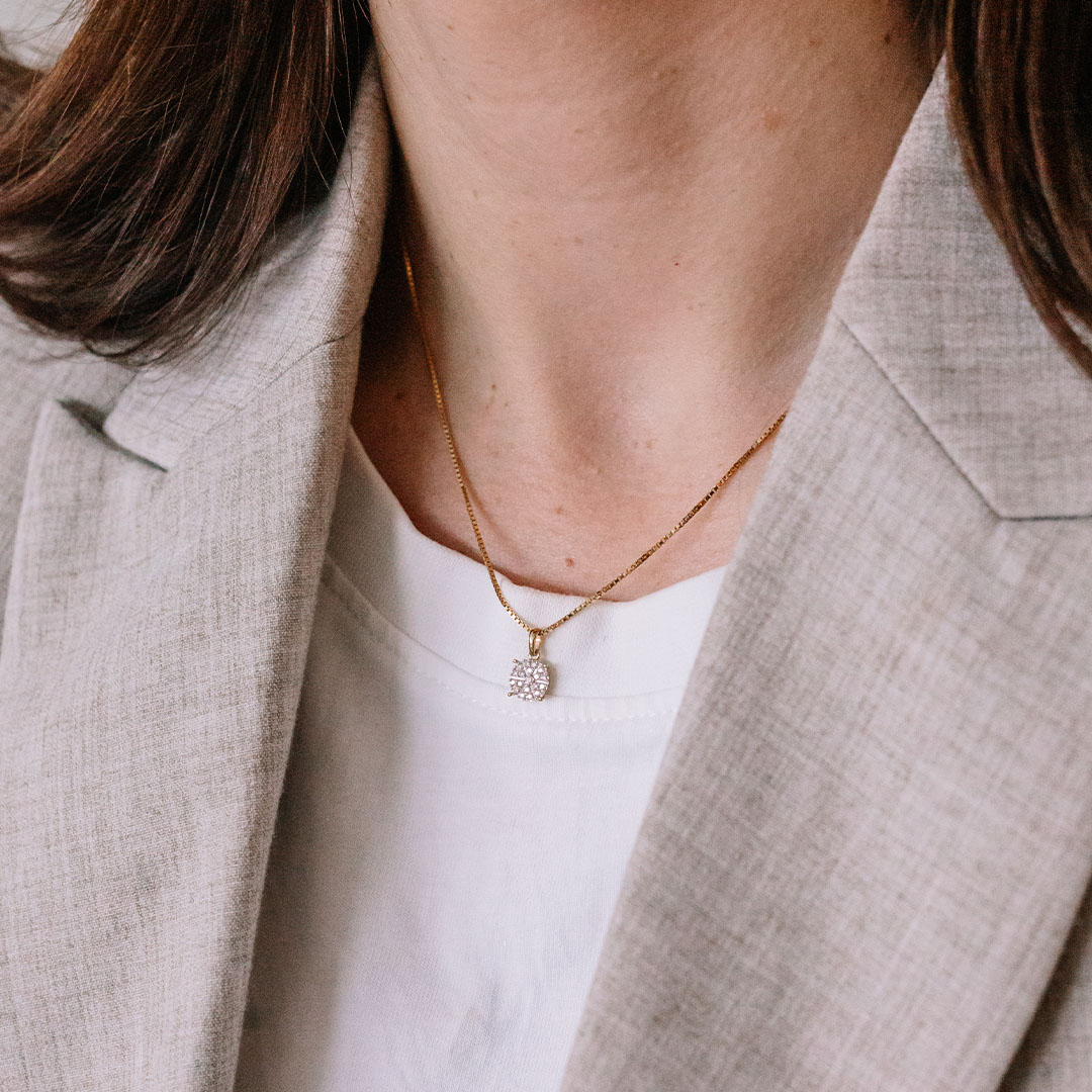 Halssmykke i gult gull med rundt anheng dekorert med stjernemønstret diamantdesign, vist mot hvit bakgrunn.