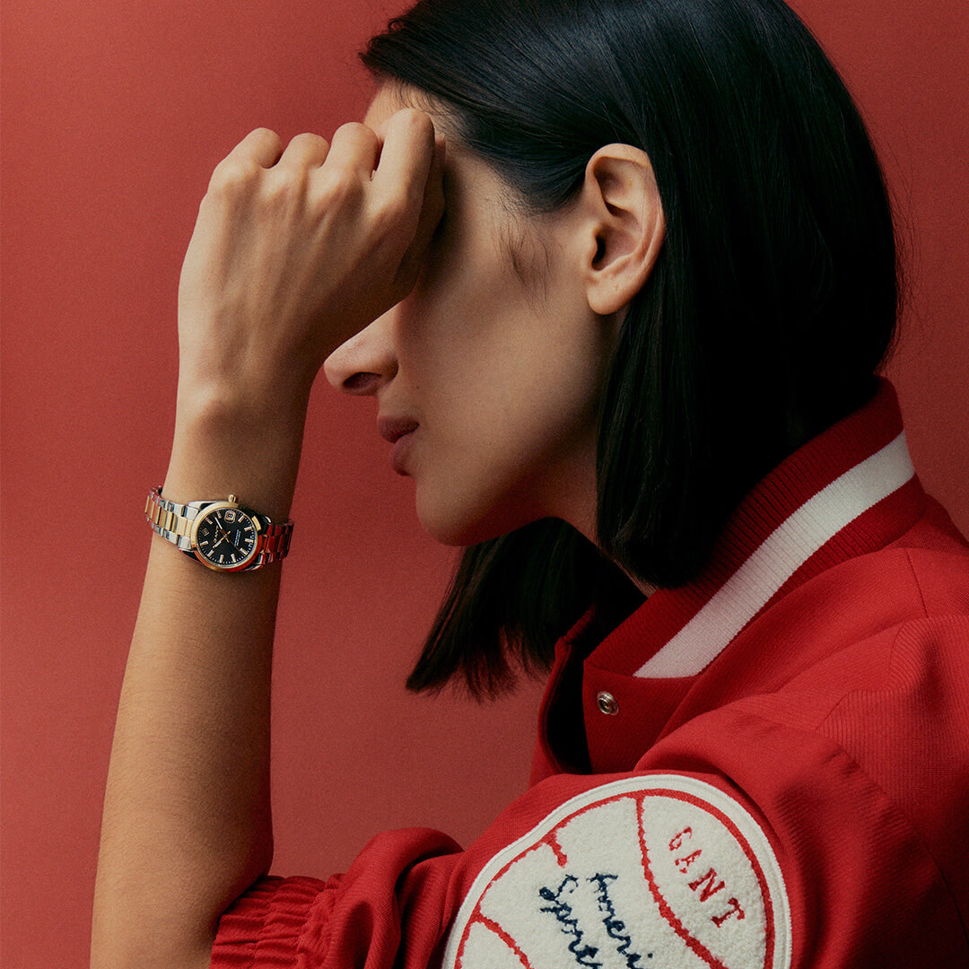 Elegant dameklokke i gull- og sølvfarget stål med sort urskive og fine detaljer i gull. Viser også dato på klokken 3.