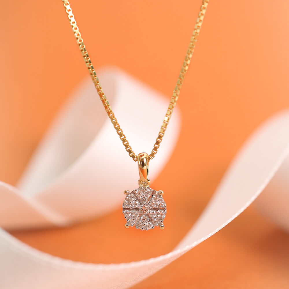 Halssmykke i gult gull med rundt anheng dekorert med stjernemønstret diamantdesign, vist mot hvit bakgrunn.