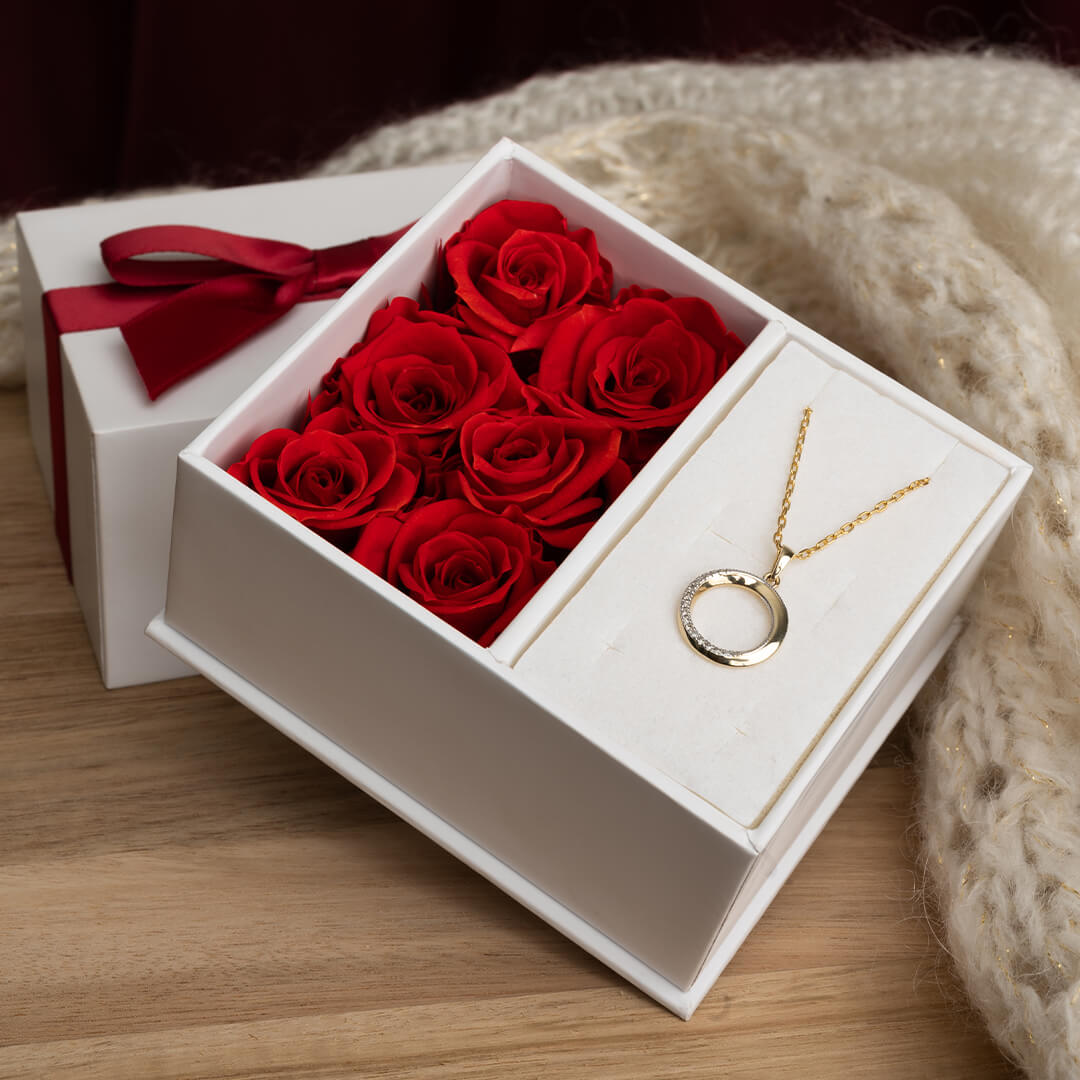 Gullkjede med rundt anheng i sirkel, dekorert med små glitrende stener langs den ene siden, vist mot hvit bakgrunn.