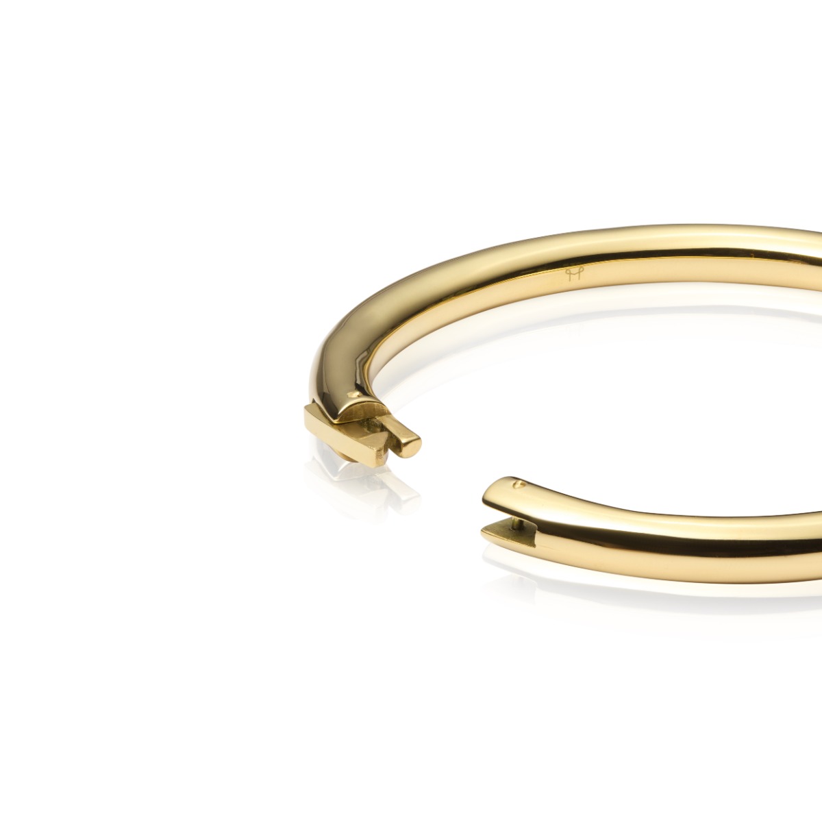 Rundt armbånd i skinnende gullfarge med jevn overflate, avbildet liggende mot hvit bakgrunn.