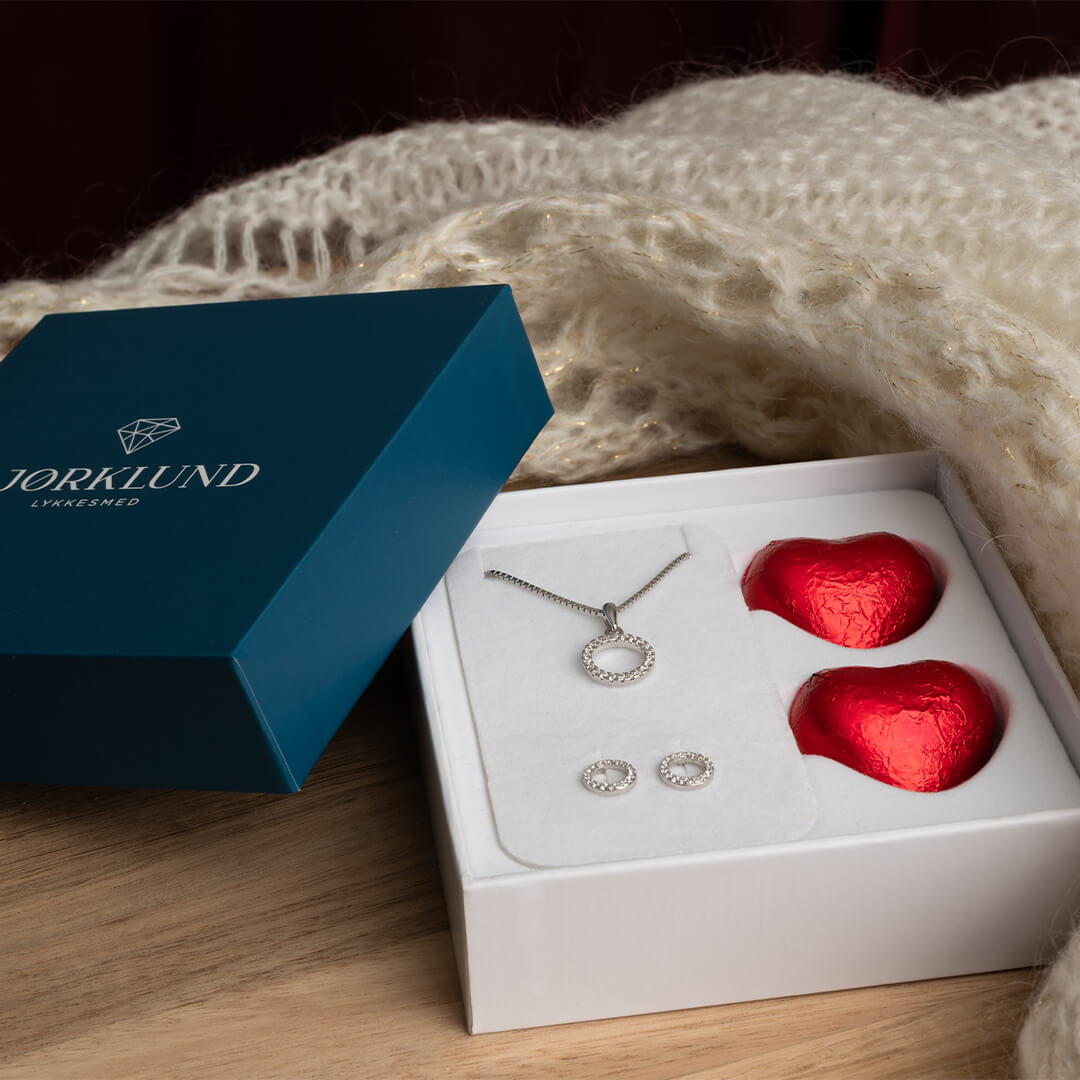 Vakre smykker med øredobber og halssmykke formet som sirkler og dekorert med glitrende hvite stener i rhodinert sølv.