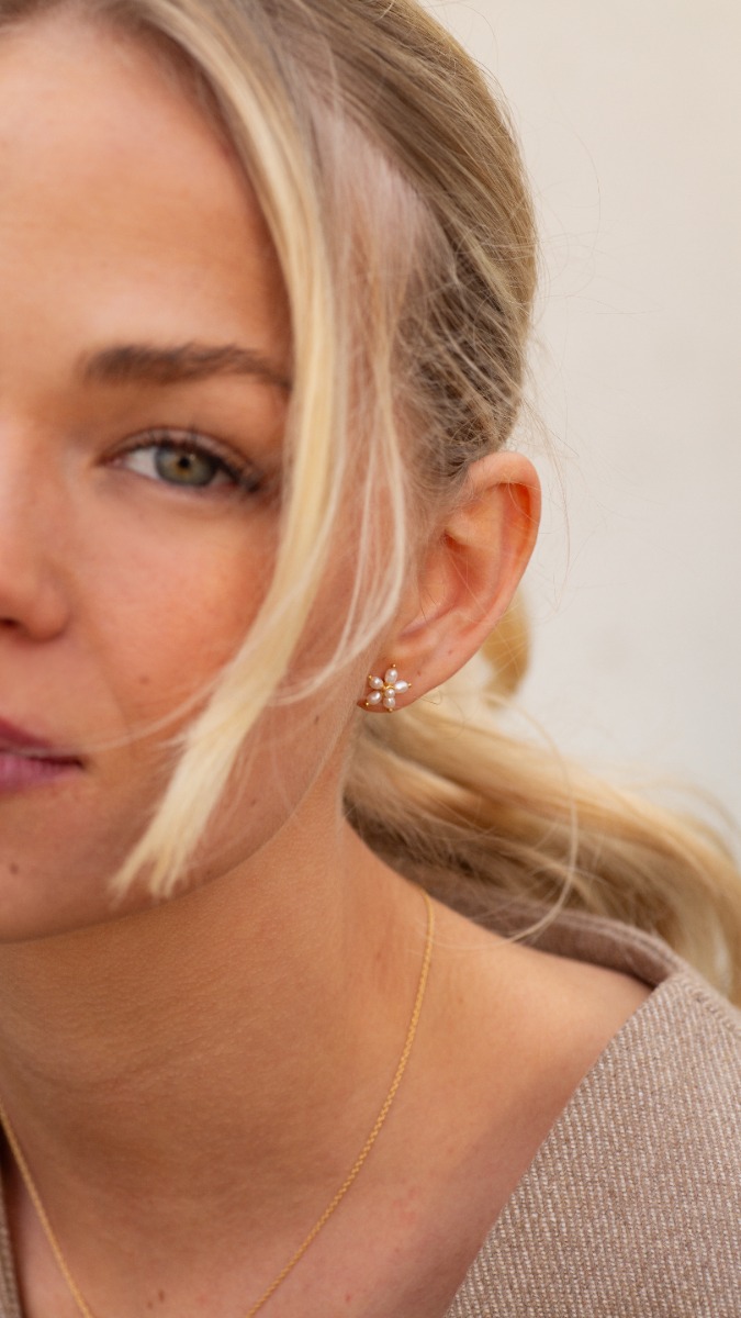 Et par øredobber i gullfarge formet som blomster med ferskvannsperler.