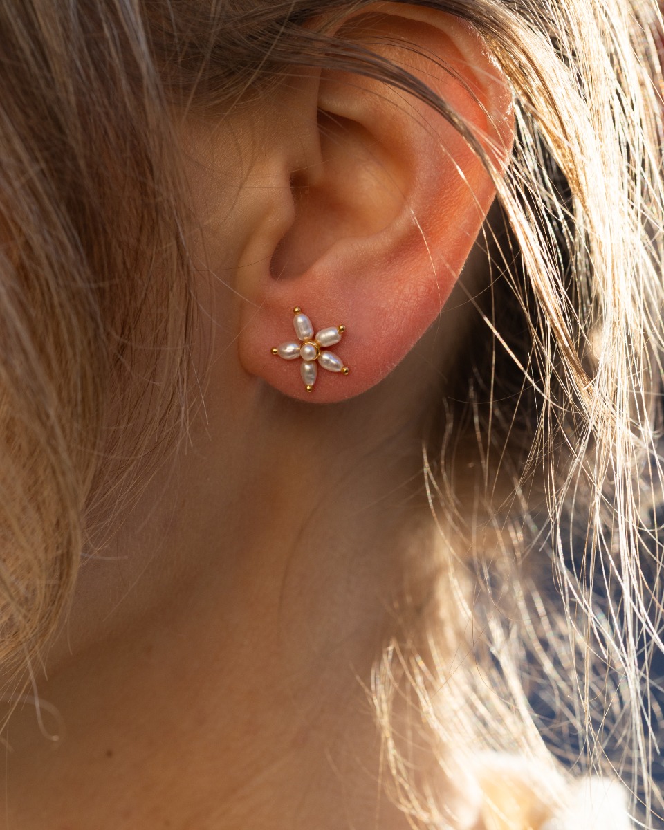 Et par øredobber i gullfarge formet som blomster med ferskvannsperler.