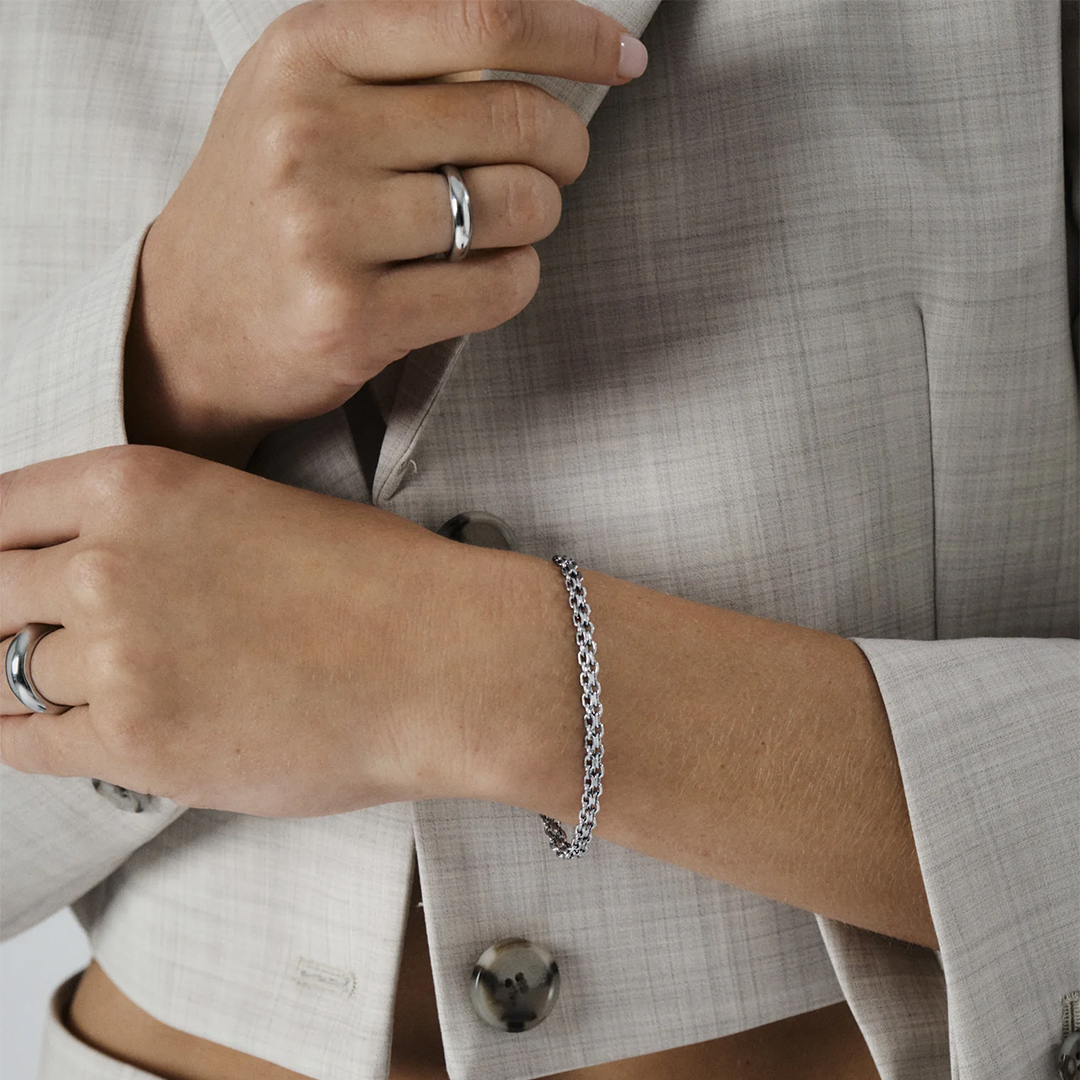 Et produktbilde av et sølvfarget armbånd med lekkert design.