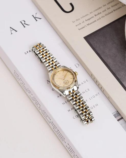 Mockberg-klokke i sølv og gull med beige urskive og liten sekundviser nederst på skiven.