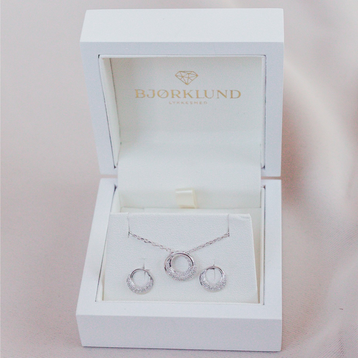 Diamantsmykke i hvitt gull med rund sirkelanheng og pavéfattet design, vist mot hvit bakgrunn.