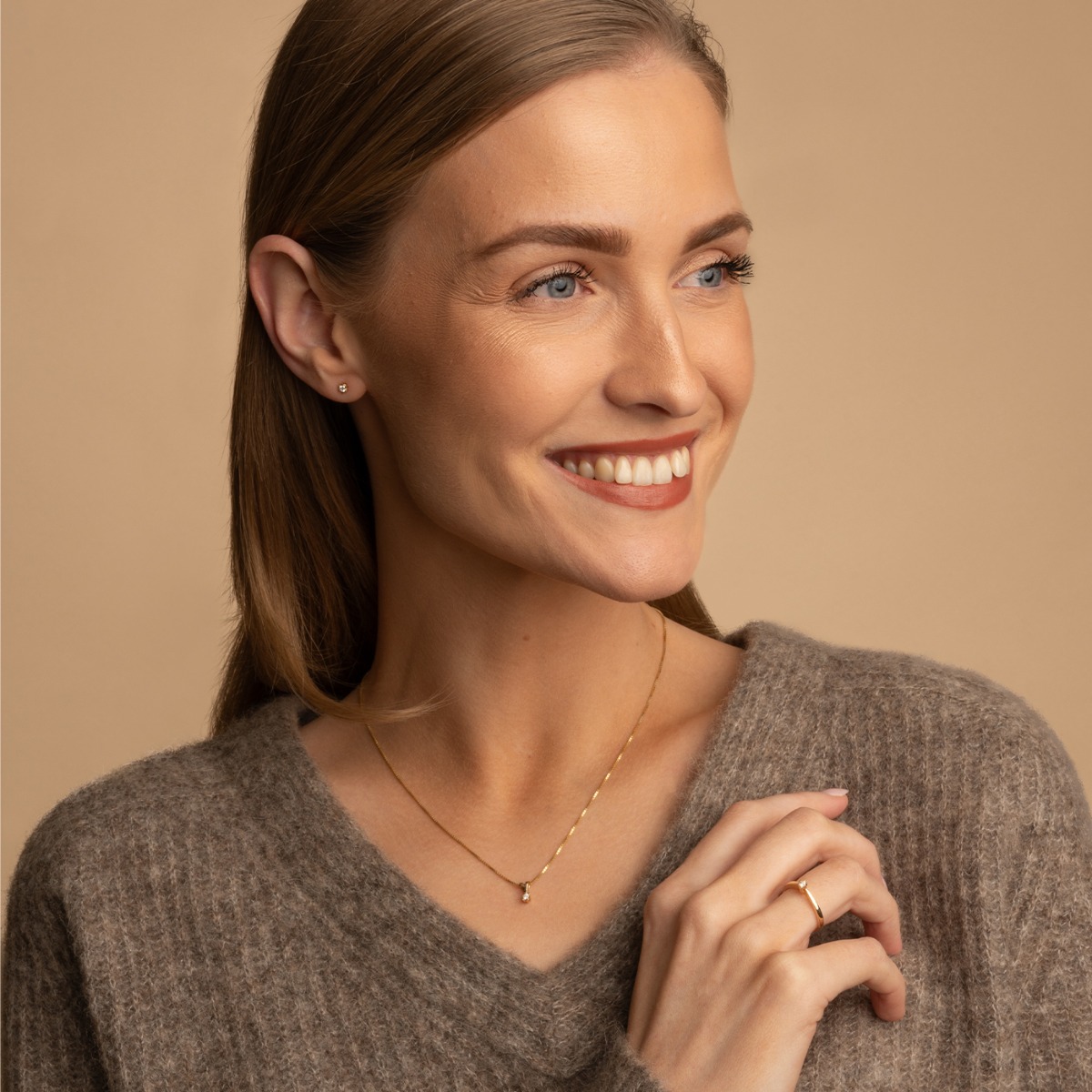 Gullkjede med anheng som holder en rund diamant i seks klør, fotografert på hvit bakgrunn med hele kjedet synlig.