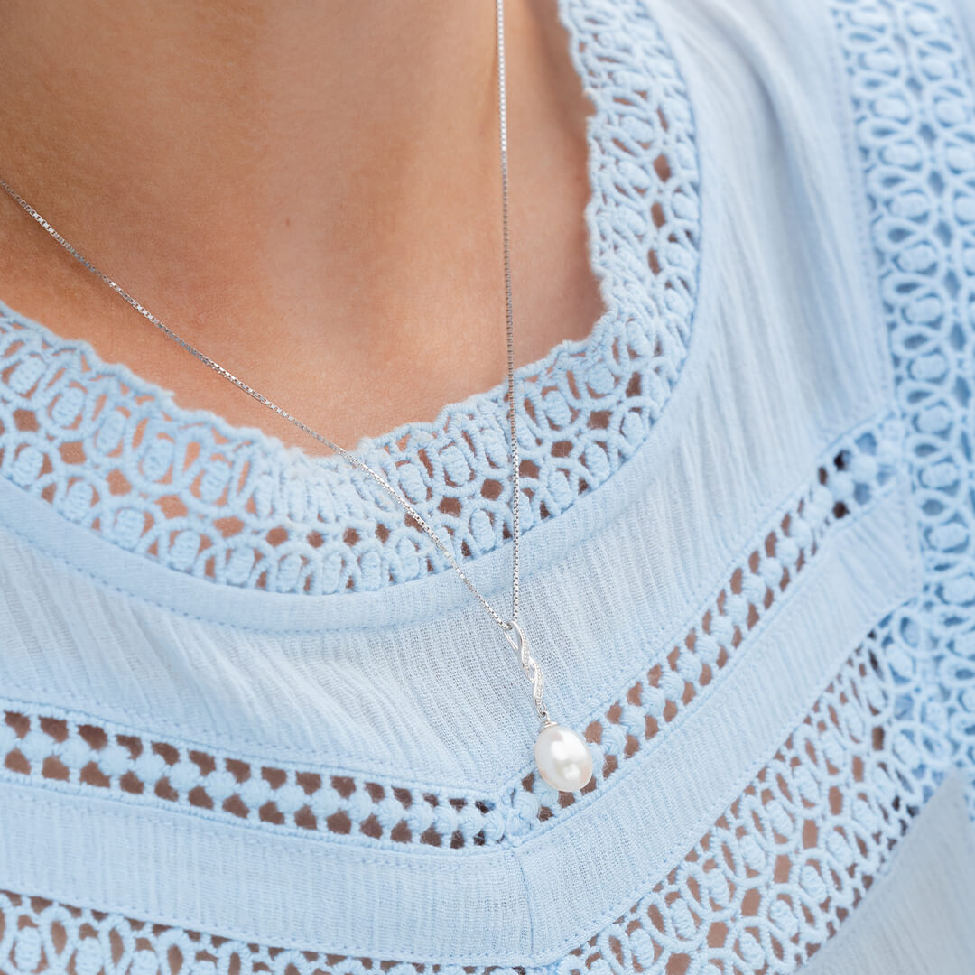 Vakkert halssmykke i hvitt gull med ferskvannsperle og hengsel dekorert med diamanter.