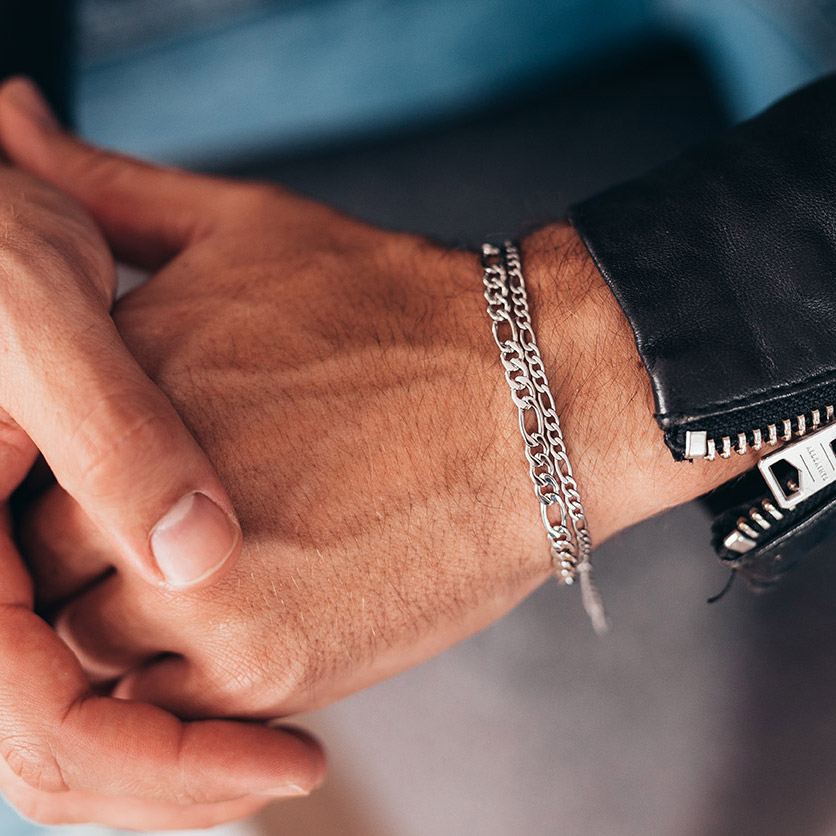 Sølvfarget armbånd med flate, ovale ledd og forlengerlenke med liten charm, vist mot hvit bakgrunn.