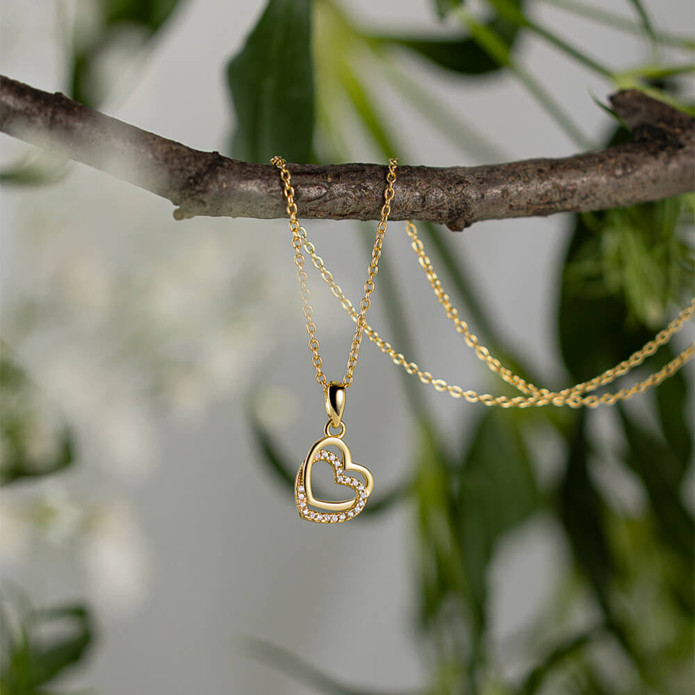 Gullkjede med anheng formet som to sammenflettede hjerter, hvor det ytterste er pyntet med små steiner