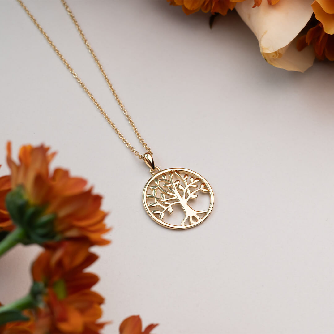 Gullkjede med rundt anheng som viser et stilisert livets tre med blank overflate, vist mot hvit bakgrunn.