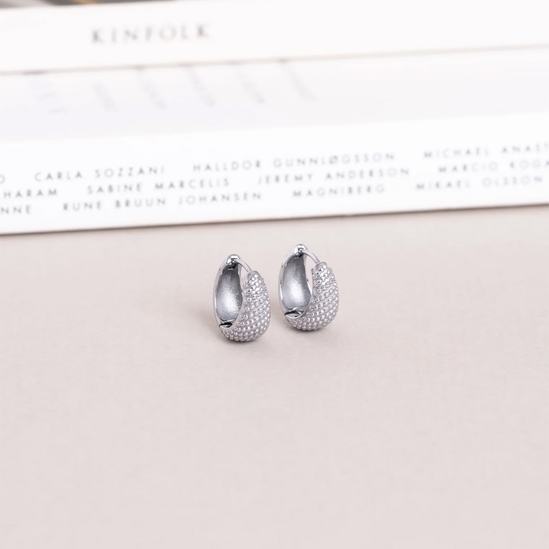 Et par øreringer med lekre detaljer som likner på prikker i sølvfarget stål.