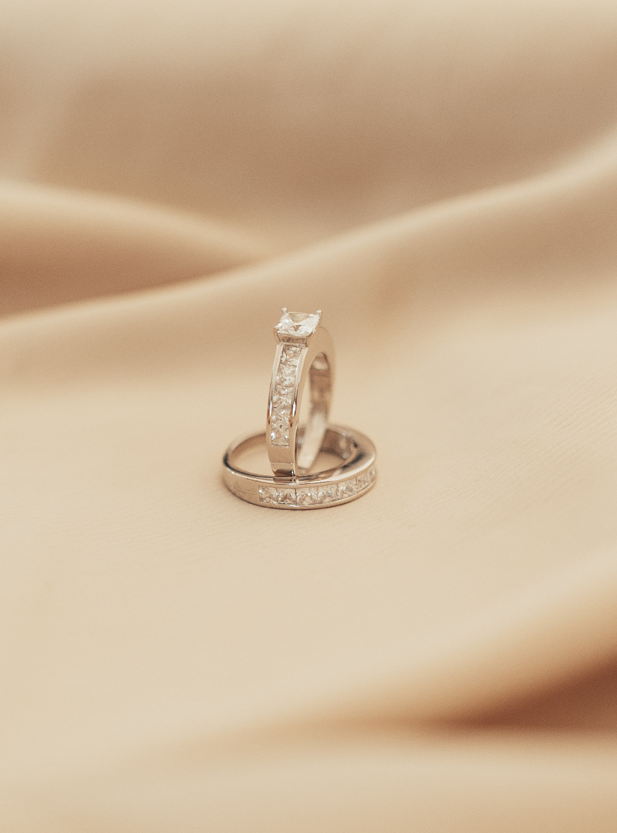 To sølvringer med rektangulære zirkonia-steiner, den ene med forhøyet midtstein i firkantet slip.