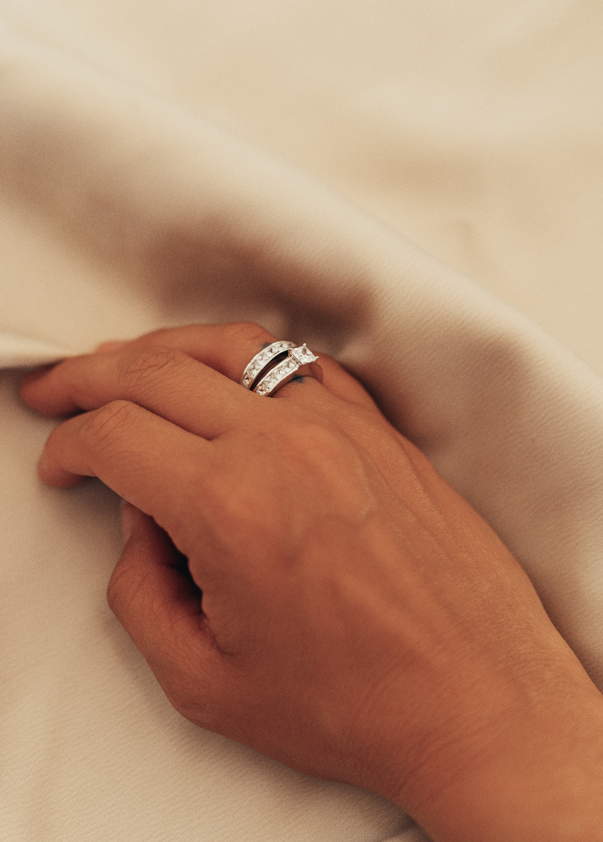 To sølvringer med rektangulære zirkonia-steiner, den ene med forhøyet midtstein i firkantet slip.