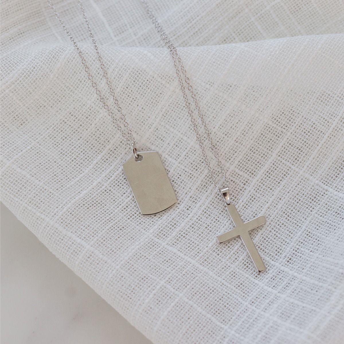 Et halssmykke i sølvfarge med anheng av kors.