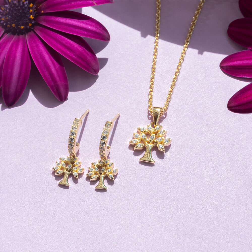 Flotte øreringer i forgylt sølv med hengende livets tre-charms, prydet med glitrende hvite stener.