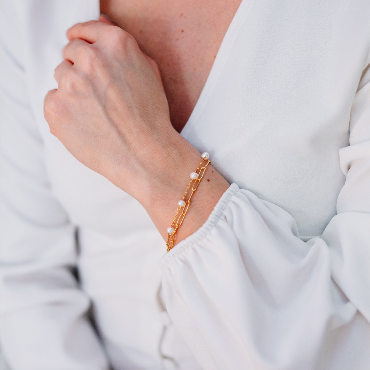 Gullfarget armbånd med to ulike lenker, en med avlange ringer og den andre med 5 perler.