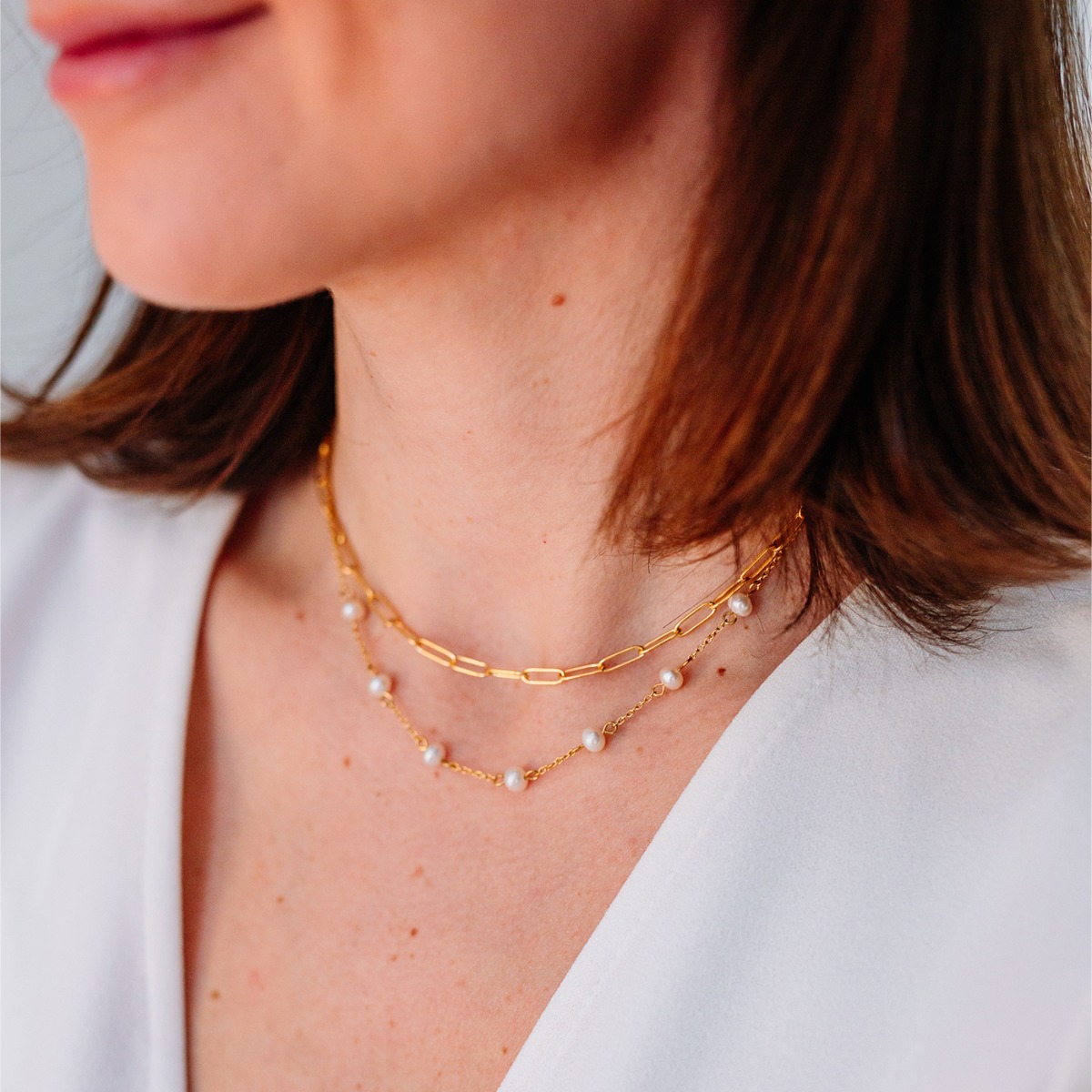 Halssmykke i gullfarge med to rader av kjeder, en lenke med avlange ringer og en annen lenke med 7 perler.