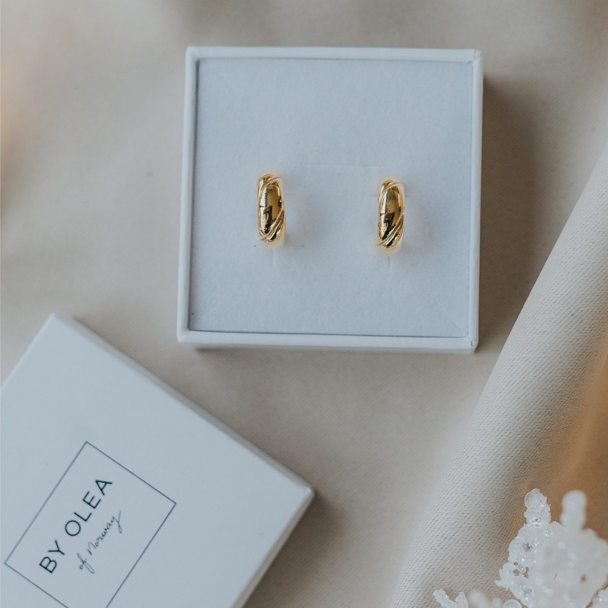 Et par øreringer i gullfarge med lekre detaljer som minner om croissant.