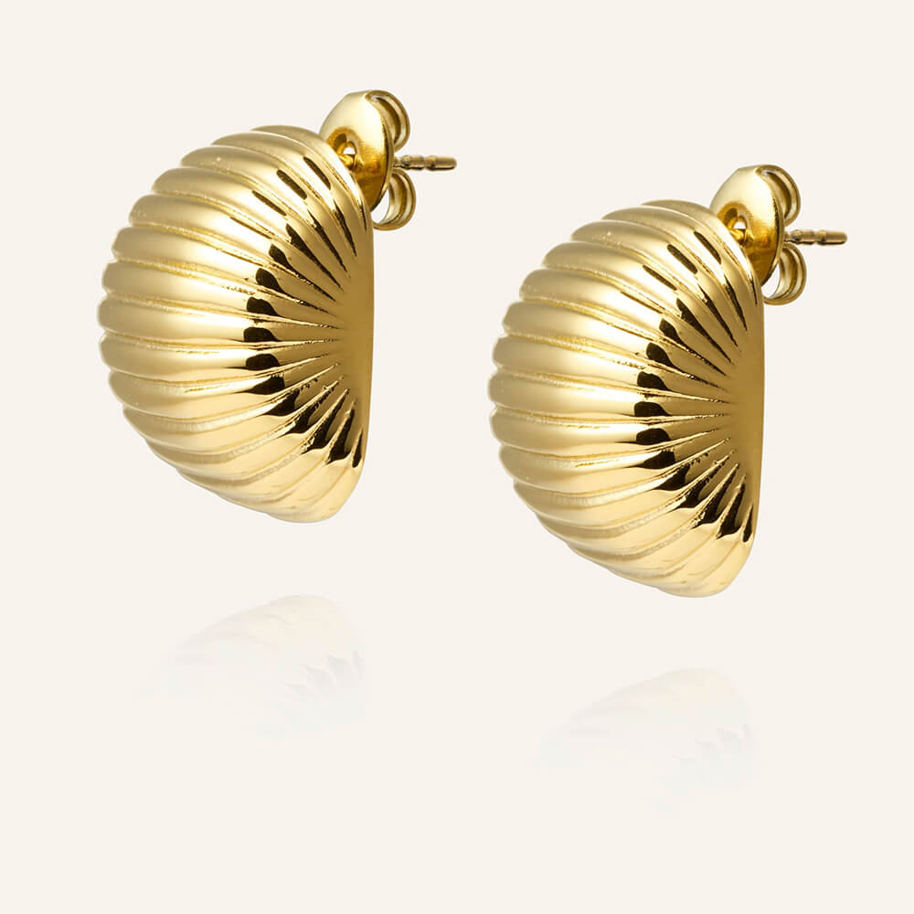 Et par gullfargede øredobber med buet form og jevne horisontale riller, avbildet mot en hvit bakgrunn med lett refleksjon.