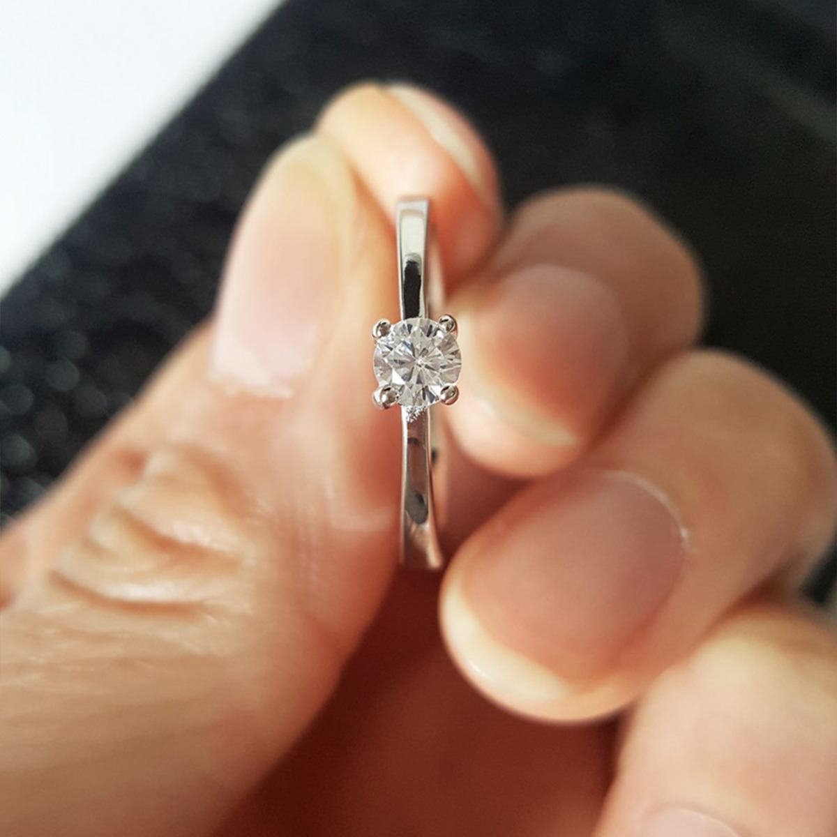 En sølvring med solitærdiamant i kløfatning vist på skrå med uskarp bakgrunn