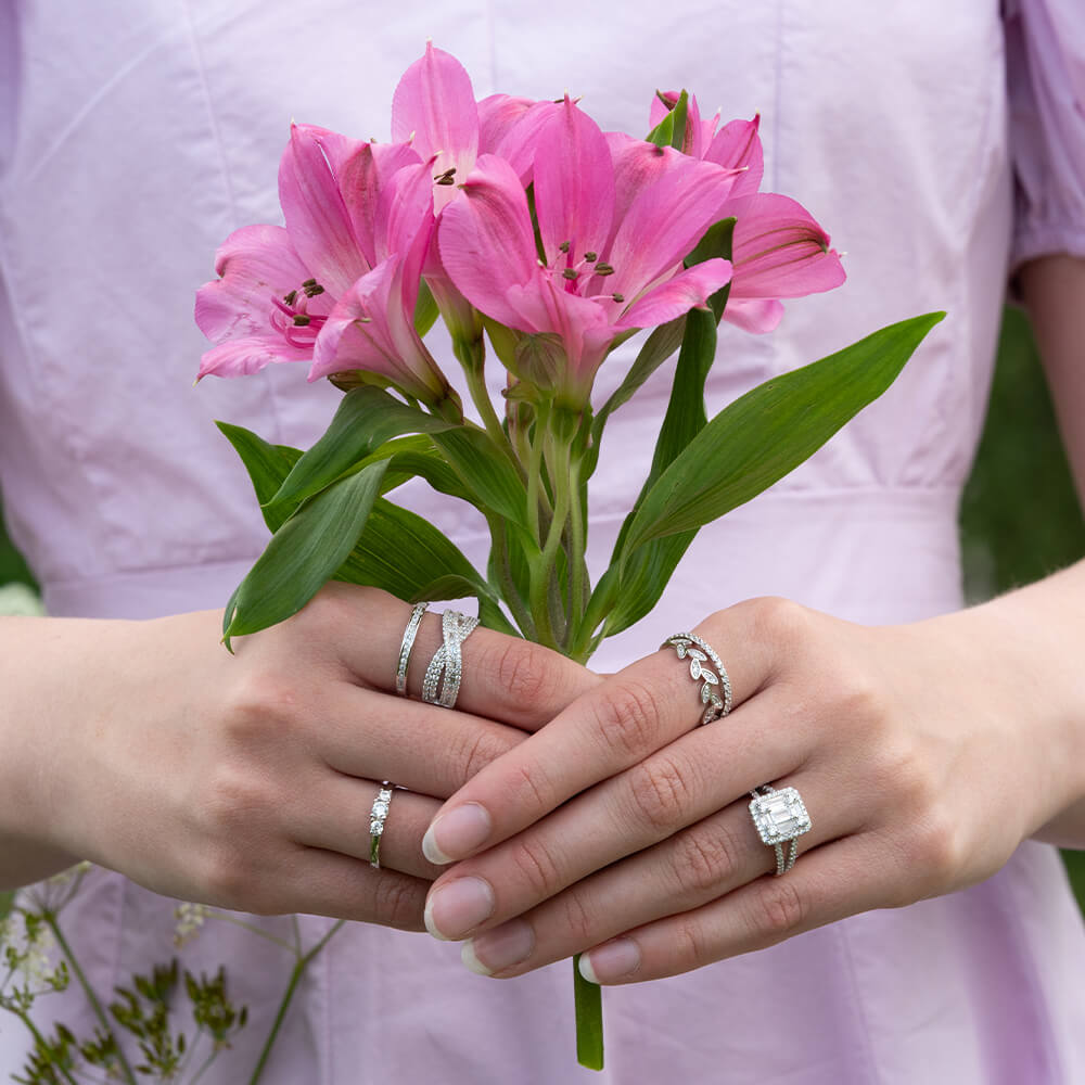 En sølvring sett forfra med rektangulær midtstengeformet topp og små steiner rundt, samt delt ringskinne med flere små steiner.