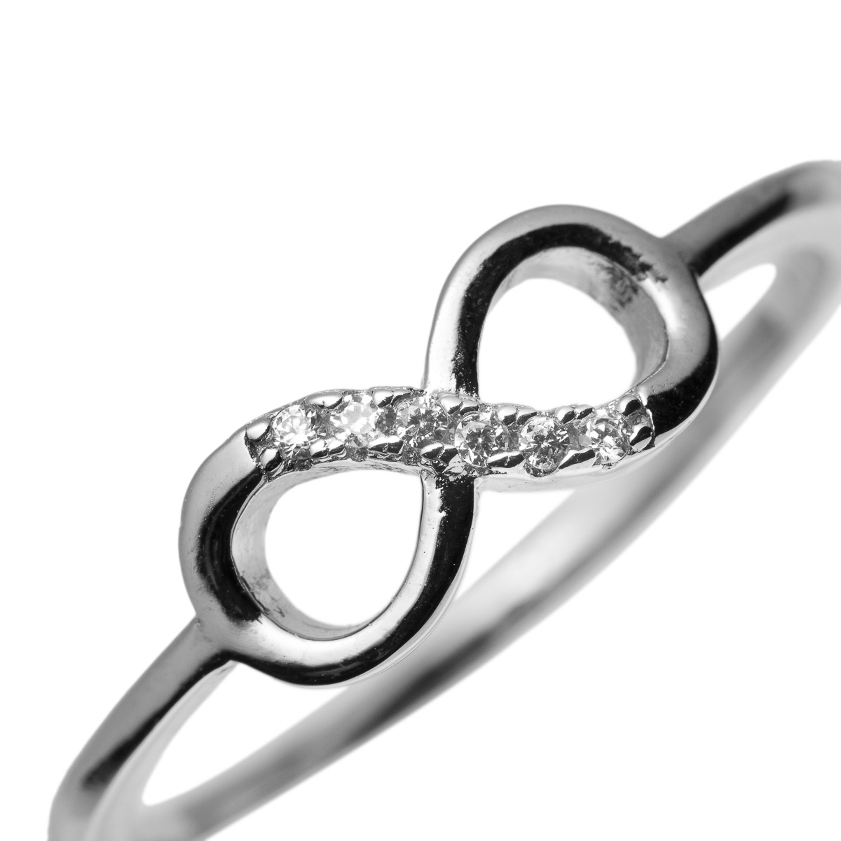 Kvinne i hvit skjorte med flere sølvringer på begge hender, inkludert en stor rektangulær ring på høyre hånd, vist fra bryst og hender.