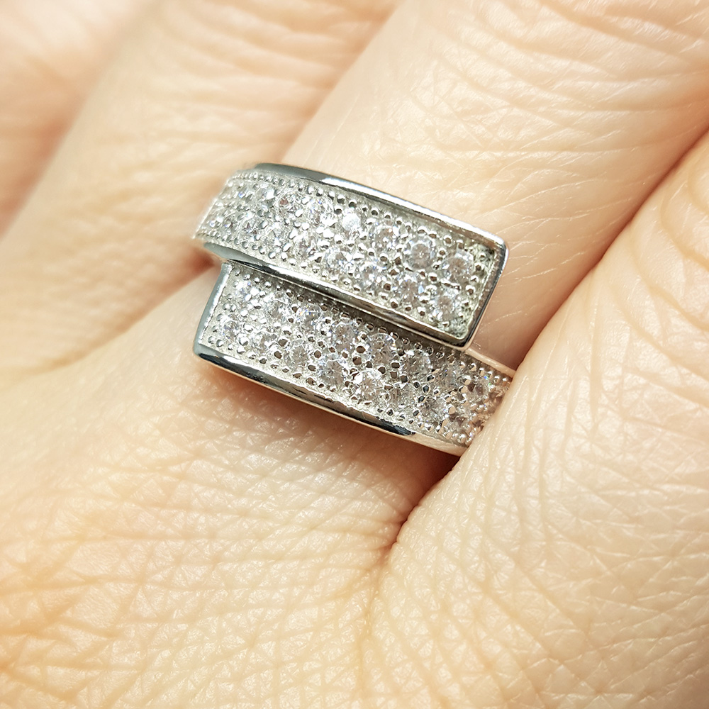 Sølvring med to parallelle skinner, besatt med små klare cubic zirkonia-steiner, mot hvit bakgrunn.