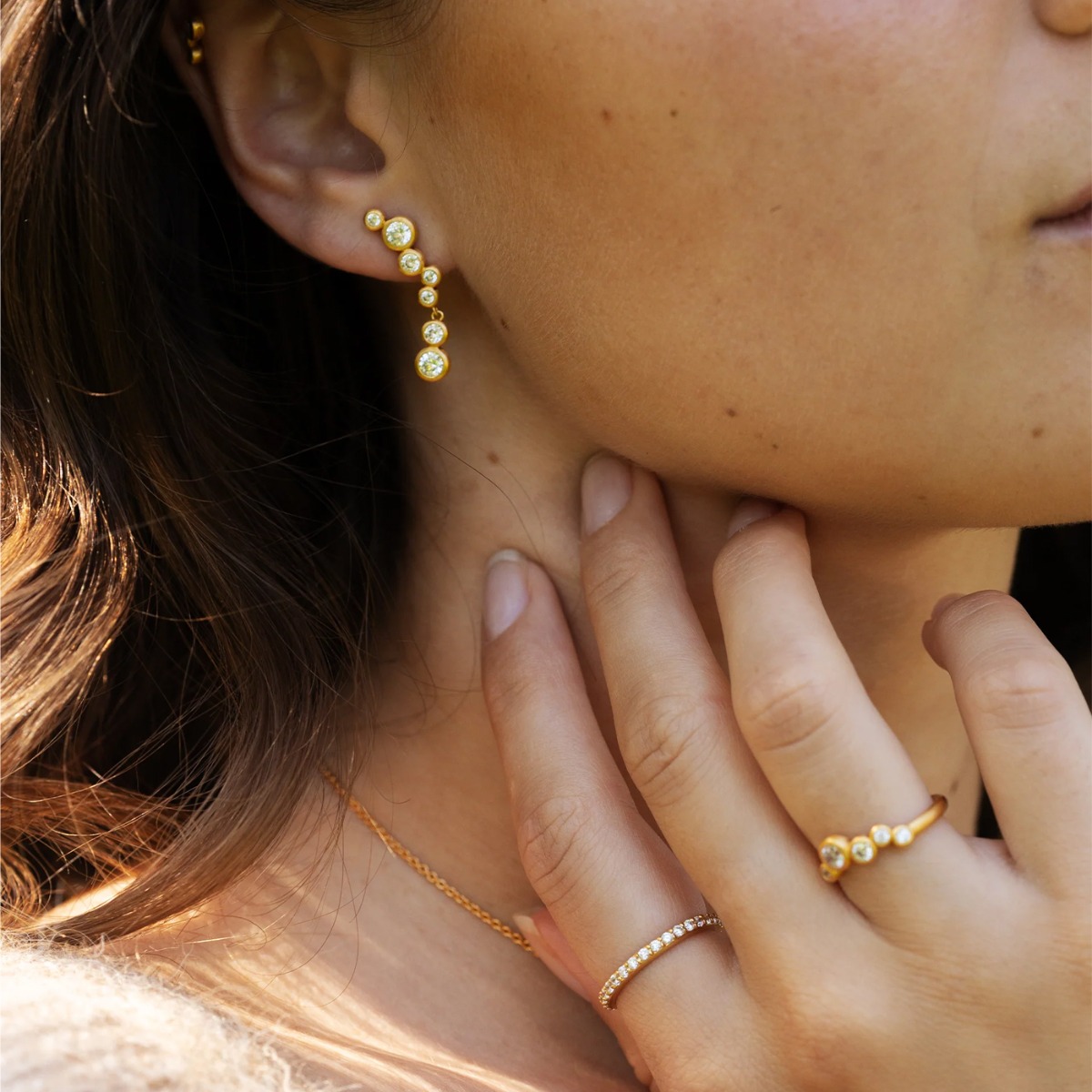 Gulløredobber med flere runde, klare stener i ulike størrelser, vist forfra og fra siden mot hvit bakgrunn.