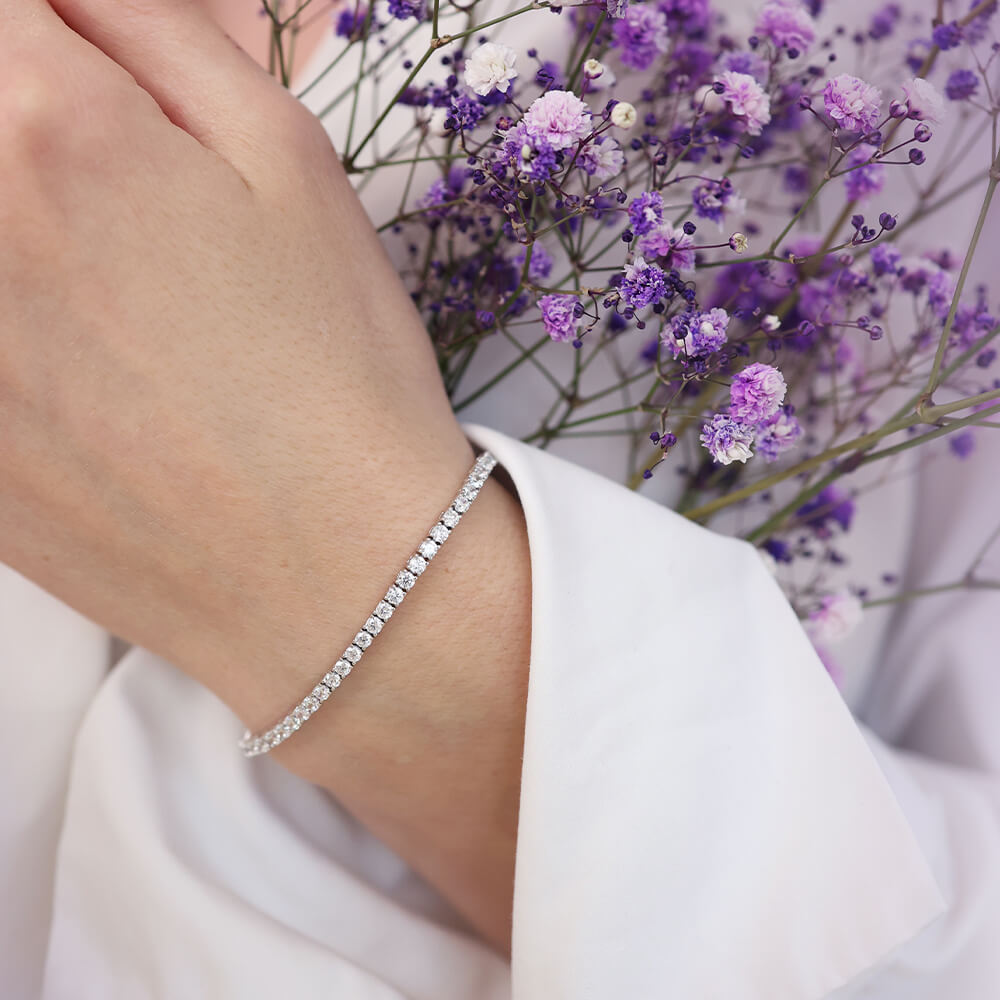 Sølvfarget tennisarmbånd med én rad runde klare steiner hele veien rundt og lås i metall midt på baksiden.